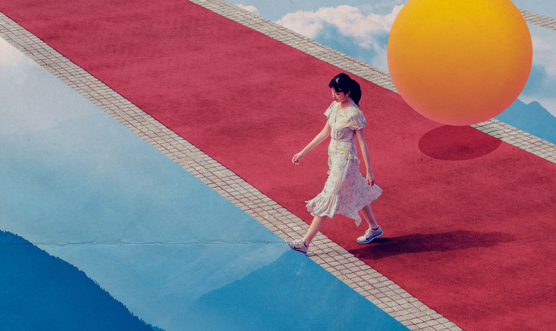 a person walking on a red carpet with a large yellow ball